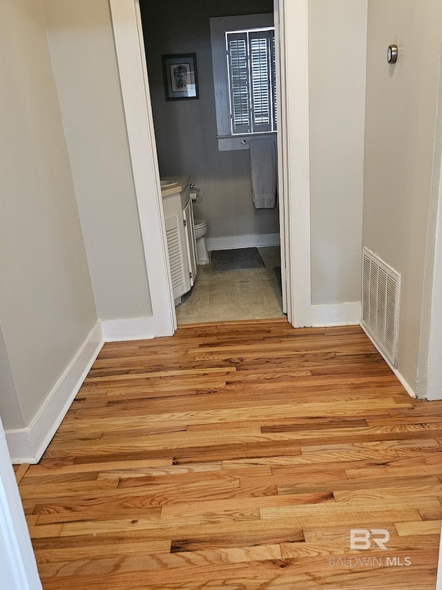 interior space with light wood-type flooring, visible vents, and baseboards