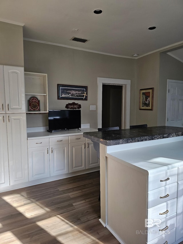 kitchen with visible vents, white cabinetry, ornamental molding, dark wood-style floors, and dark countertops