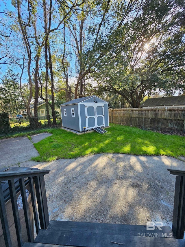 view of yard with an outbuilding, a patio, a storage unit, and a fenced backyard