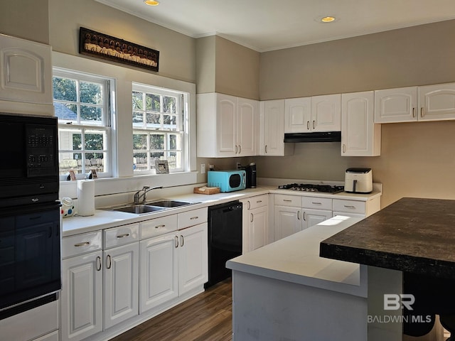 kitchen with dark wood-type flooring, white cabinets, a sink, under cabinet range hood, and black appliances