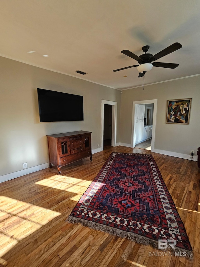 living area with ornamental molding, light wood finished floors, visible vents, and baseboards