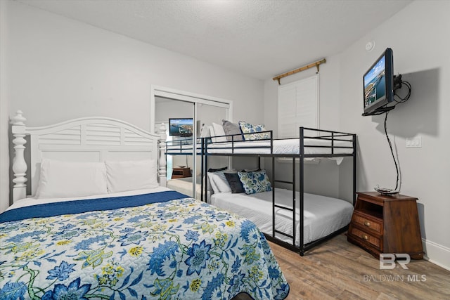 bedroom with a textured ceiling, hardwood / wood-style flooring, and a closet