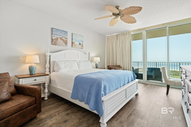 bedroom with access to exterior, floor to ceiling windows, ceiling fan, dark wood-type flooring, and a water view