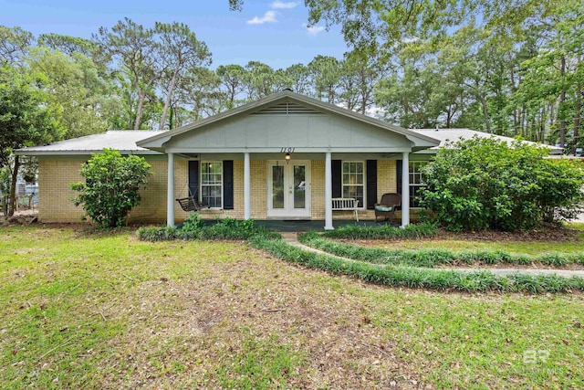 1101 Alabama Ave, Dauphin Island, AL 36528 - view of front of property featuring french doors, covered porch, brick siding, and a front yard