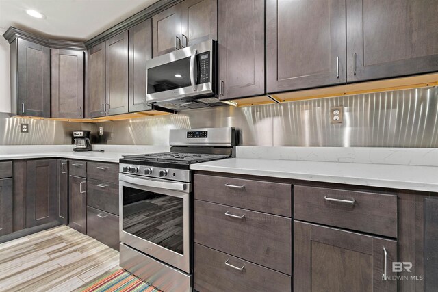 1101 Alabama Ave, Dauphin Island, AL 36528 - kitchen with stainless steel appliances, dark brown cabinets, and light wood finished floors