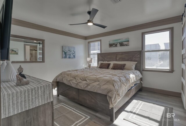 bedroom with crown molding, ceiling fan, and light wood-type flooring