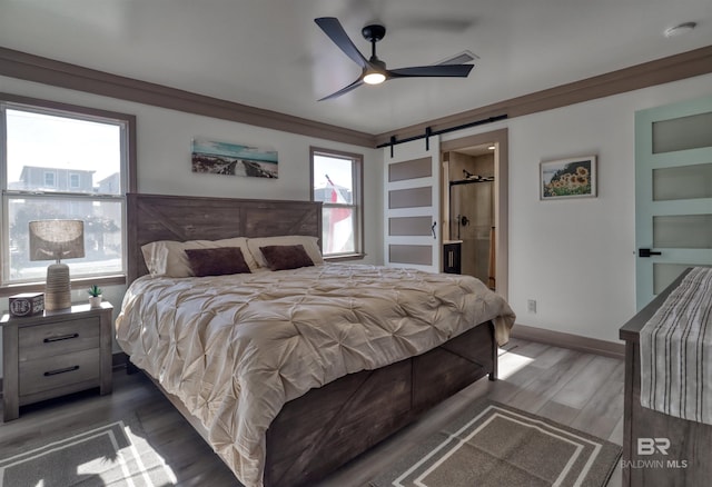 bedroom with crown molding, dark hardwood / wood-style floors, ensuite bathroom, and a barn door
