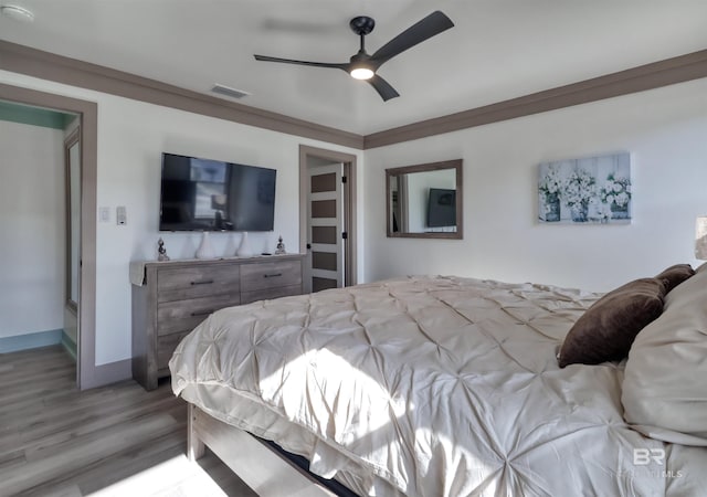 bedroom featuring ornamental molding, ceiling fan, and light hardwood / wood-style flooring