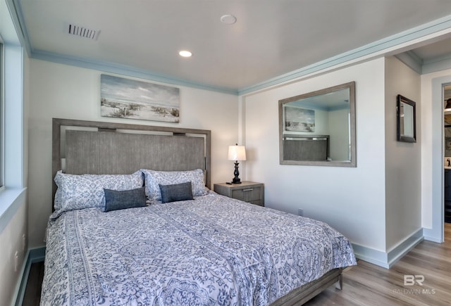 bedroom with ornamental molding and light wood-type flooring