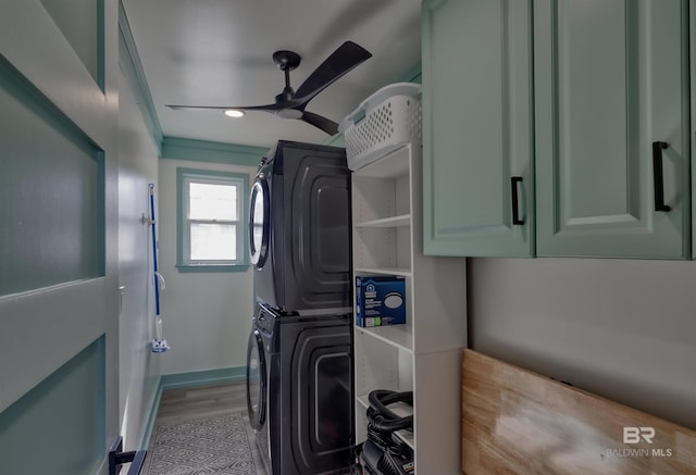 laundry room featuring stacked washer and dryer, light hardwood / wood-style floors, cabinets, and ceiling fan