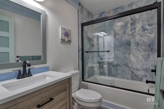 full bathroom with vanity, enclosed tub / shower combo, and toilet