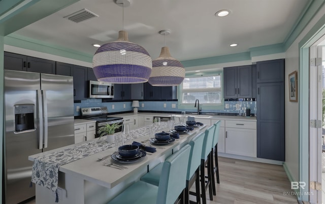 kitchen with pendant lighting, white cabinetry, appliances with stainless steel finishes, and a breakfast bar