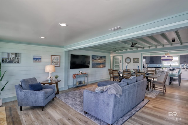living room featuring beam ceiling and light hardwood / wood-style flooring