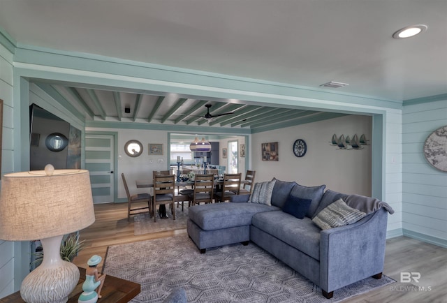 living room with wood-type flooring, beamed ceiling, and wood walls