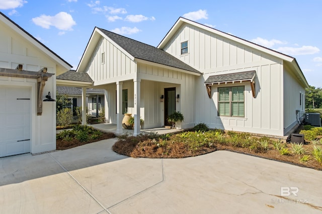 modern inspired farmhouse with a porch, a garage, and central air condition unit