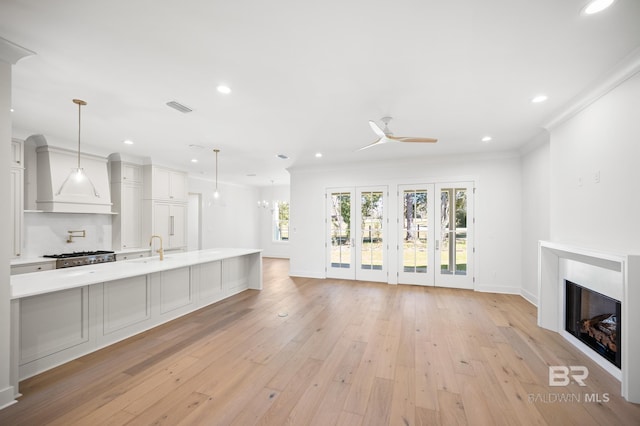 unfurnished living room featuring ceiling fan, light hardwood / wood-style flooring, sink, and ornamental molding