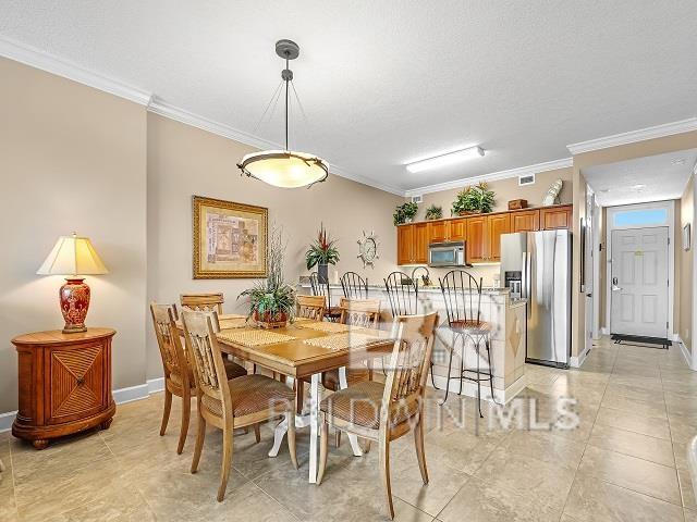 tiled dining room featuring crown molding and a textured ceiling