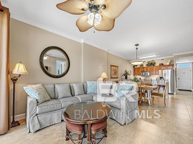 tiled living room featuring ornamental molding and ceiling fan