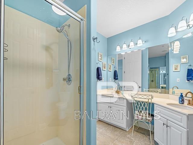 bathroom with vanity, tile floors, and a shower with shower door