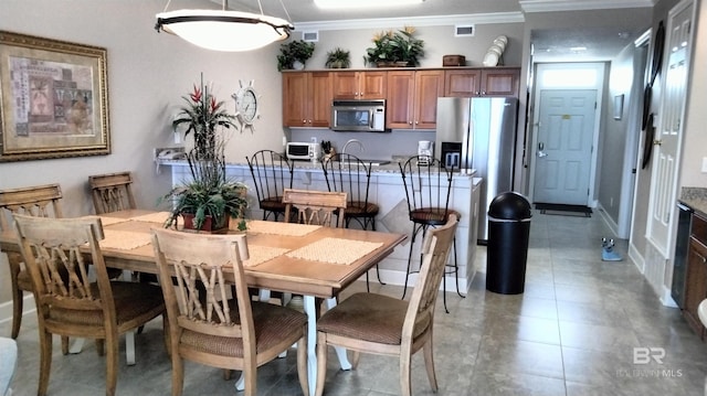 dining area featuring crown molding and light tile floors