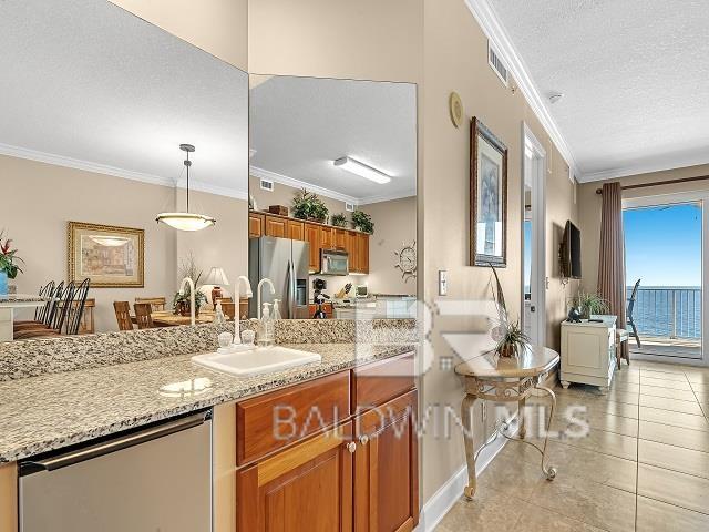 kitchen featuring appliances with stainless steel finishes, crown molding, pendant lighting, a textured ceiling, and sink