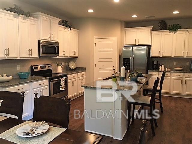 kitchen featuring white cabinets, an island with sink, and stainless steel appliances