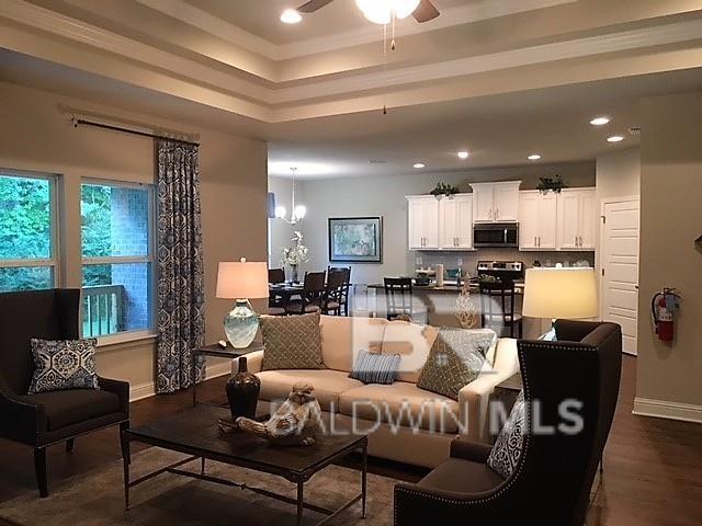 living room with ceiling fan with notable chandelier and dark hardwood / wood-style flooring