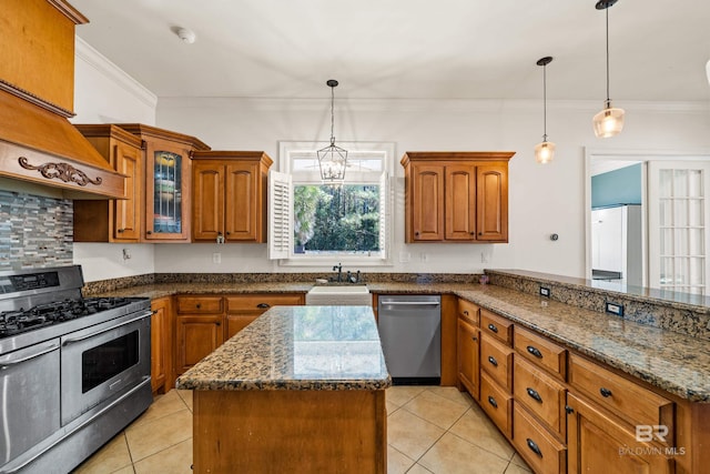 kitchen with sink, light tile patterned flooring, stainless steel appliances, and decorative light fixtures