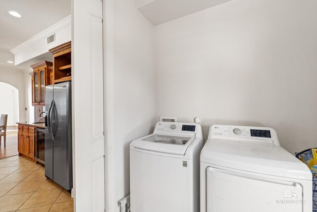 laundry area with washing machine and dryer, light tile patterned floors, and beverage cooler