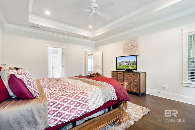 bedroom featuring a raised ceiling, dark hardwood / wood-style flooring, ceiling fan, and crown molding