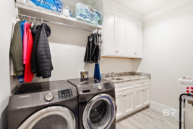 laundry area featuring cabinets, crown molding, sink, independent washer and dryer, and light hardwood / wood-style floors