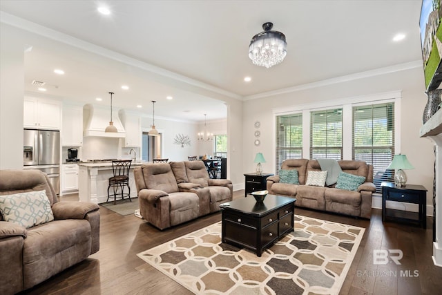 living room with hardwood / wood-style flooring, crown molding, and an inviting chandelier