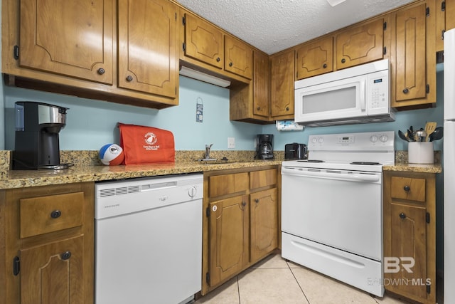 kitchen featuring white appliances, sink, light stone countertops, a textured ceiling, and light tile patterned flooring