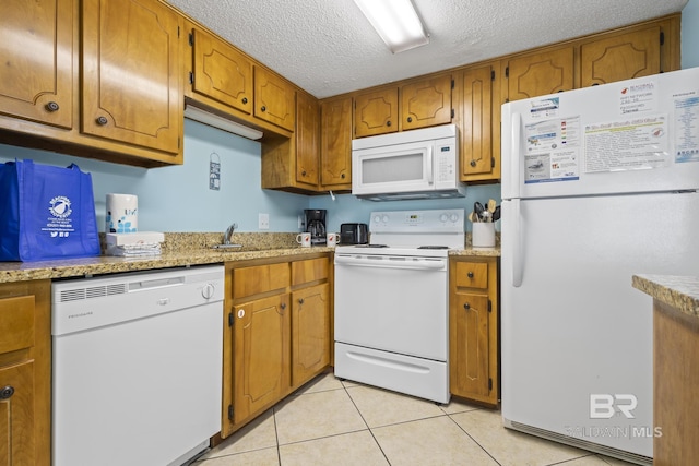 kitchen with sink, white appliances, a textured ceiling, and light tile patterned floors