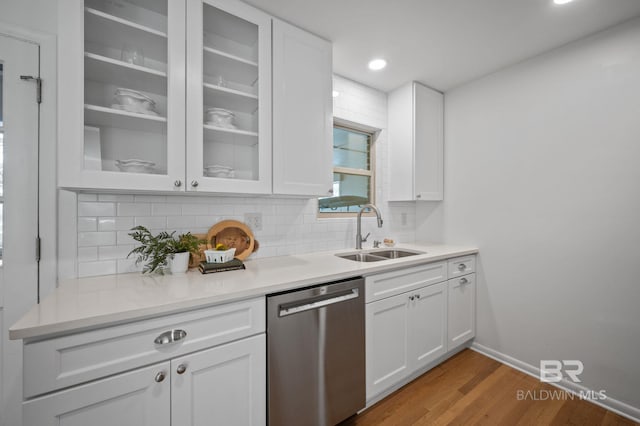 kitchen with a sink, white cabinets, glass insert cabinets, dishwasher, and tasteful backsplash