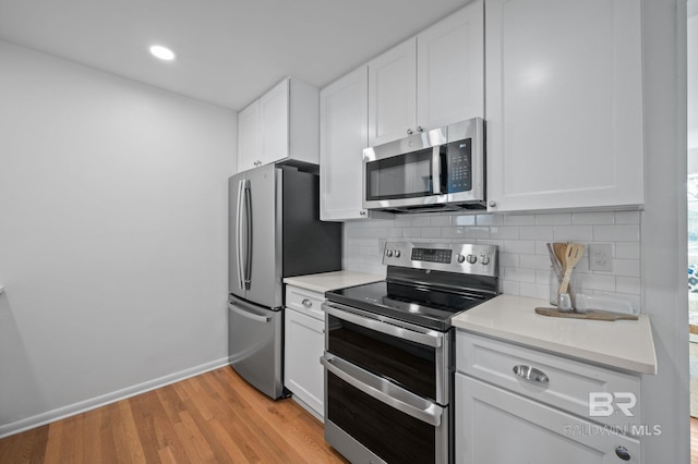 kitchen with tasteful backsplash, light wood finished floors, light countertops, stainless steel appliances, and white cabinetry