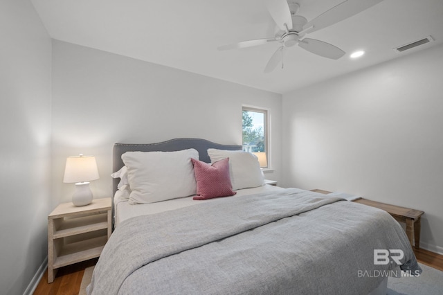 bedroom featuring visible vents, ceiling fan, baseboards, and wood finished floors