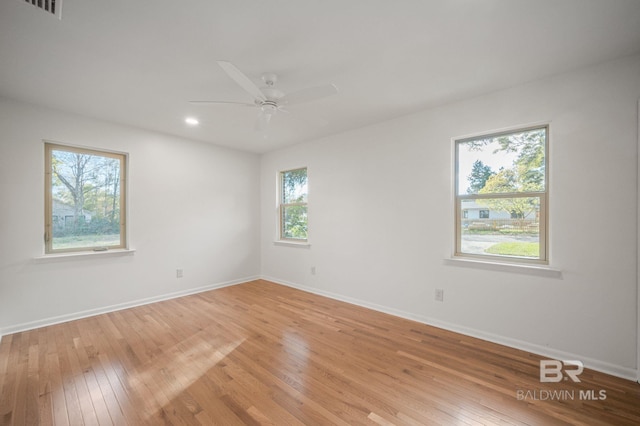 empty room with visible vents, a ceiling fan, baseboards, and light wood finished floors