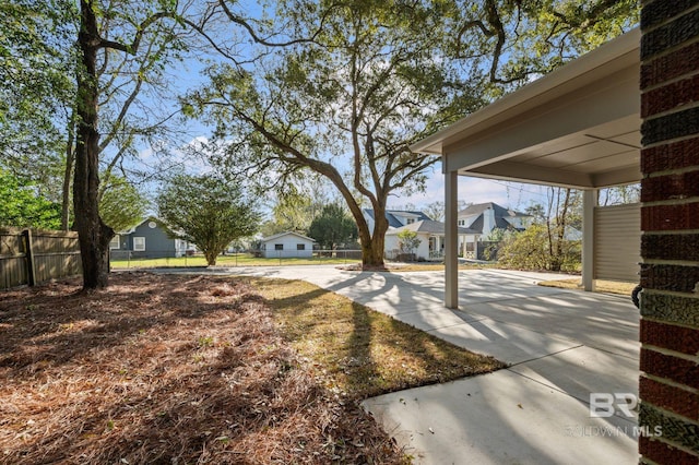 view of yard with concrete driveway, fence, and a residential view