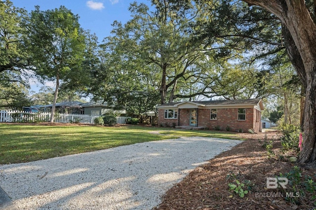 single story home with gravel driveway, a front lawn, fence, and brick siding