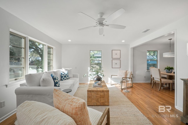 living area featuring a ceiling fan, wood finished floors, visible vents, baseboards, and recessed lighting
