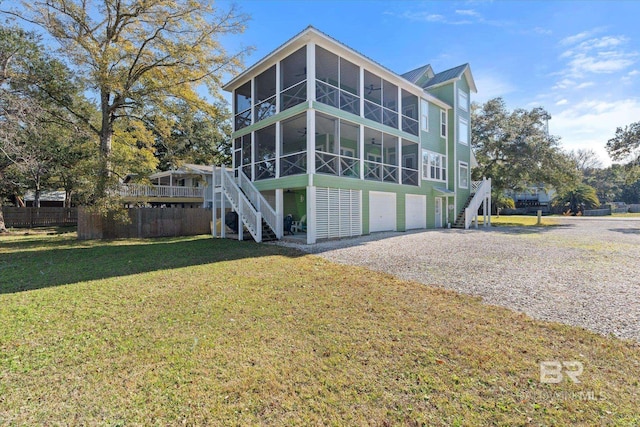 exterior space with a garage, a sunroom, and a yard