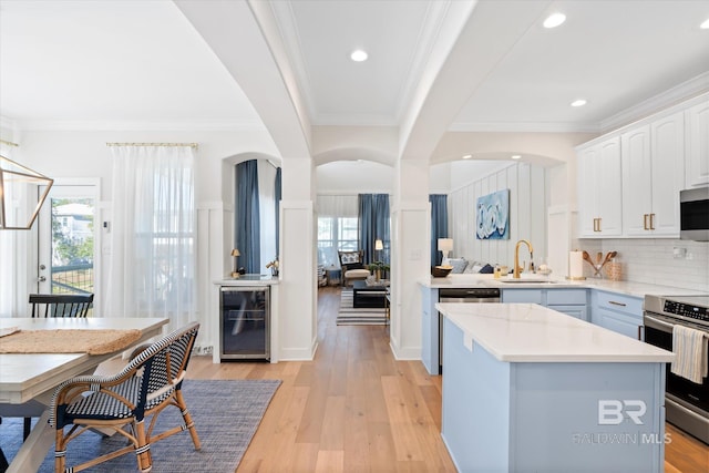 kitchen with white cabinets, a center island, stainless steel appliances, wine cooler, and sink