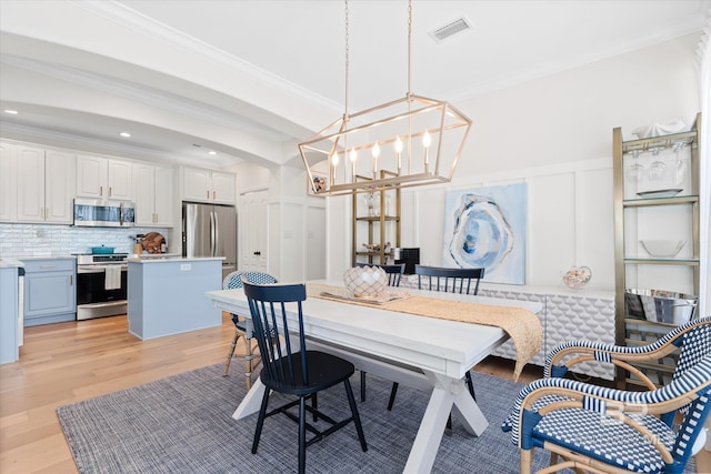 dining room with ornamental molding, light hardwood / wood-style flooring, and a notable chandelier