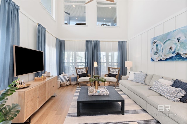 living room with a towering ceiling and light hardwood / wood-style flooring