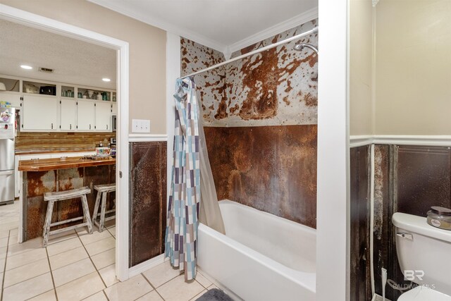 bathroom with tile patterned floors, crown molding, toilet, shower / bath combo with shower curtain, and tile walls