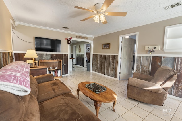 living room featuring ceiling fan, wood walls, a textured ceiling, and ornamental molding