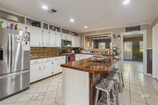 kitchen featuring a breakfast bar, a center island, white cabinets, ornamental molding, and appliances with stainless steel finishes