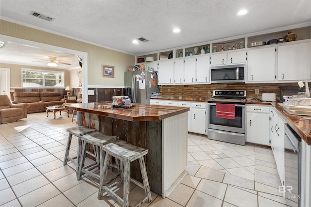 kitchen featuring a breakfast bar area, white cabinets, a textured ceiling, and appliances with stainless steel finishes