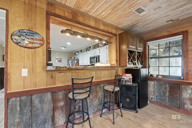 bar featuring light hardwood / wood-style floors, wooden walls, stainless steel appliances, and wooden ceiling